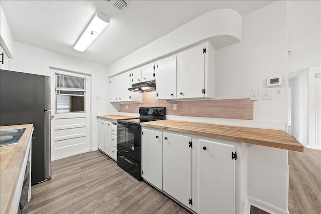 kitchen featuring white cabinets, stainless steel fridge, black / electric stove, butcher block countertops, and light hardwood / wood-style floors