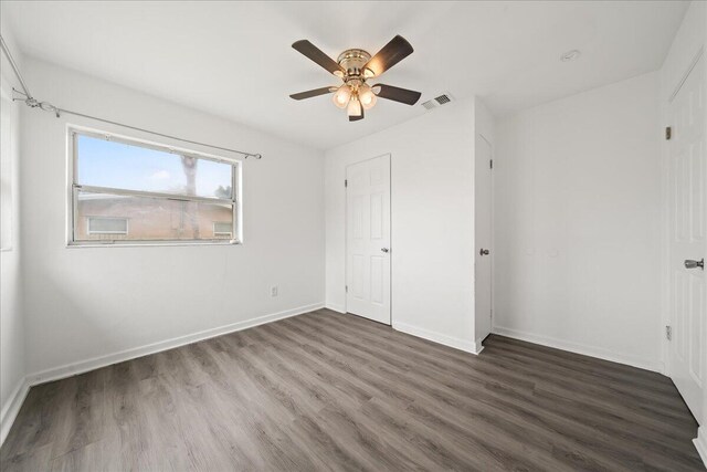 unfurnished bedroom with ceiling fan and dark wood-type flooring