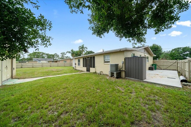 rear view of house with central air condition unit, a yard, and a patio