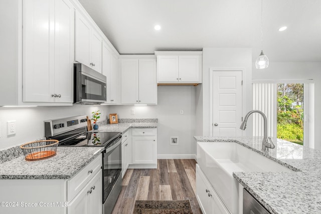 kitchen with hanging light fixtures, sink, white cabinetry, light stone countertops, and stainless steel appliances