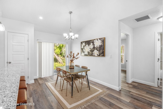 dining room with dark wood-type flooring, vaulted ceiling, and an inviting chandelier