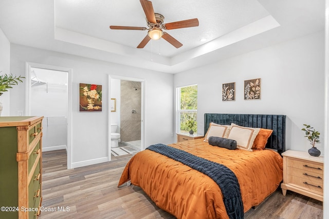 bedroom with ensuite bath, a closet, a spacious closet, and a tray ceiling