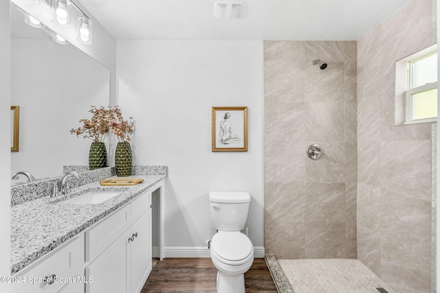 bathroom with hardwood / wood-style floors, toilet, vanity, and tiled shower