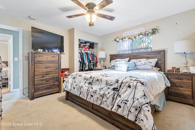 bedroom with ceiling fan, light colored carpet, and a closet