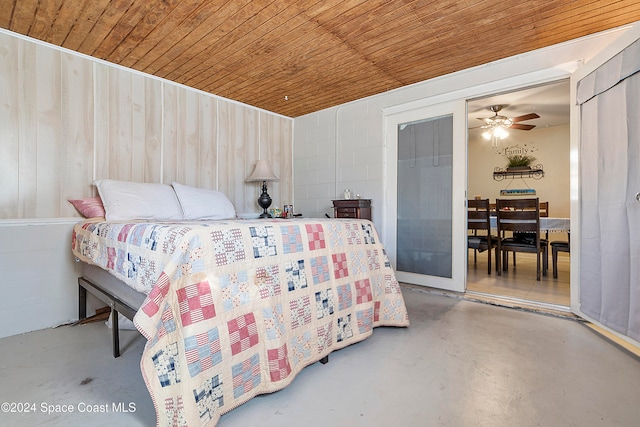 bedroom with ceiling fan, wood ceiling, wooden walls, and concrete floors