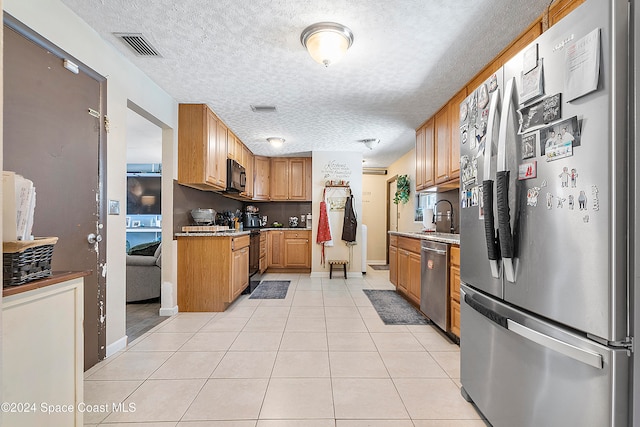 kitchen featuring light tile patterned floors, a textured ceiling, stainless steel appliances, and sink