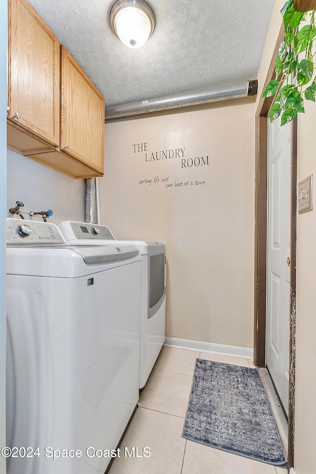 washroom featuring separate washer and dryer, light tile patterned floors, cabinets, and a textured ceiling