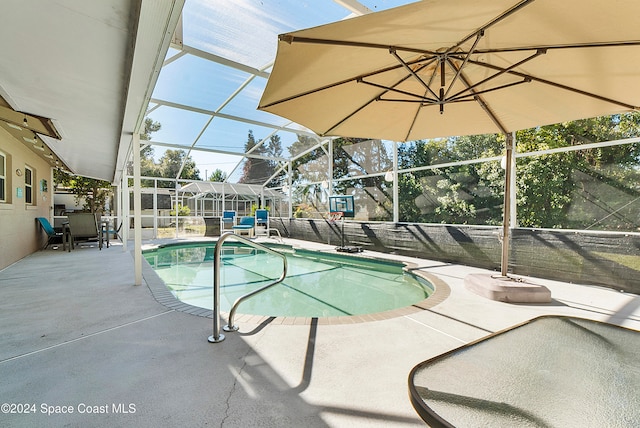 view of pool with glass enclosure and a patio area