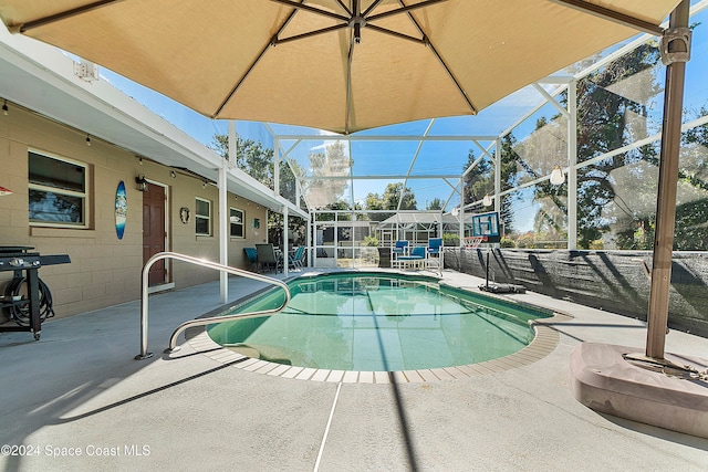 view of swimming pool featuring glass enclosure and a patio