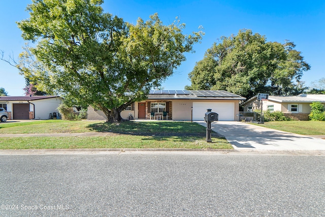 single story home with solar panels, a garage, and a front lawn