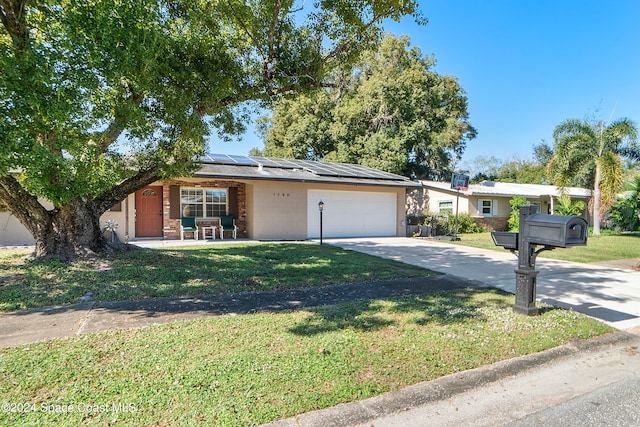 single story home with a front yard, solar panels, and a garage