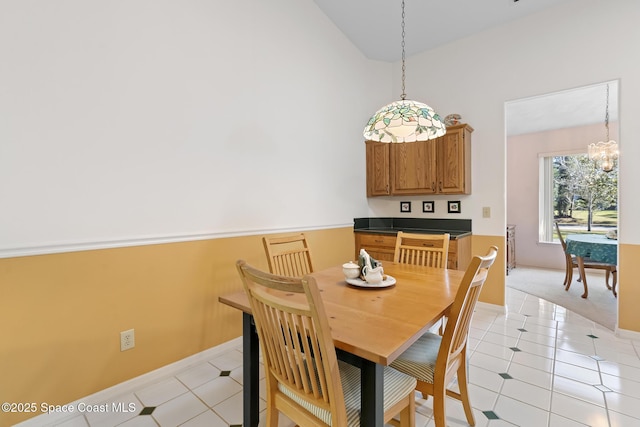 dining room featuring high vaulted ceiling, light tile patterned floors, and an inviting chandelier