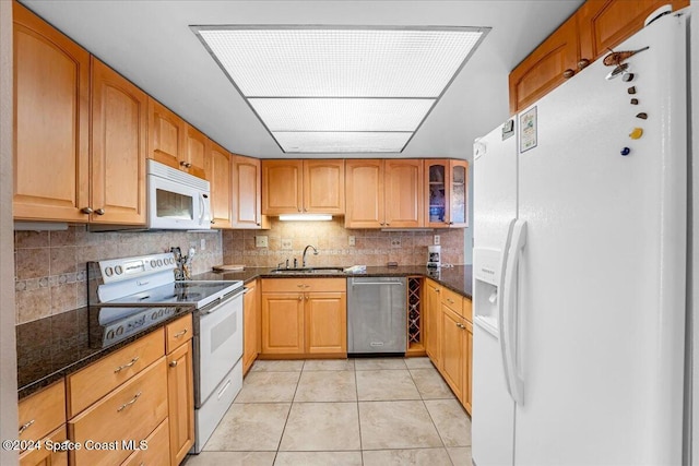 kitchen featuring white appliances, sink, light tile patterned floors, and dark stone counters