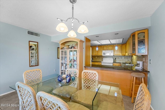 dining space with sink, tile patterned flooring, a textured ceiling, and an inviting chandelier