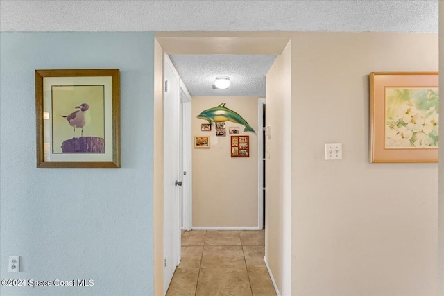 hall featuring a textured ceiling and light tile patterned flooring