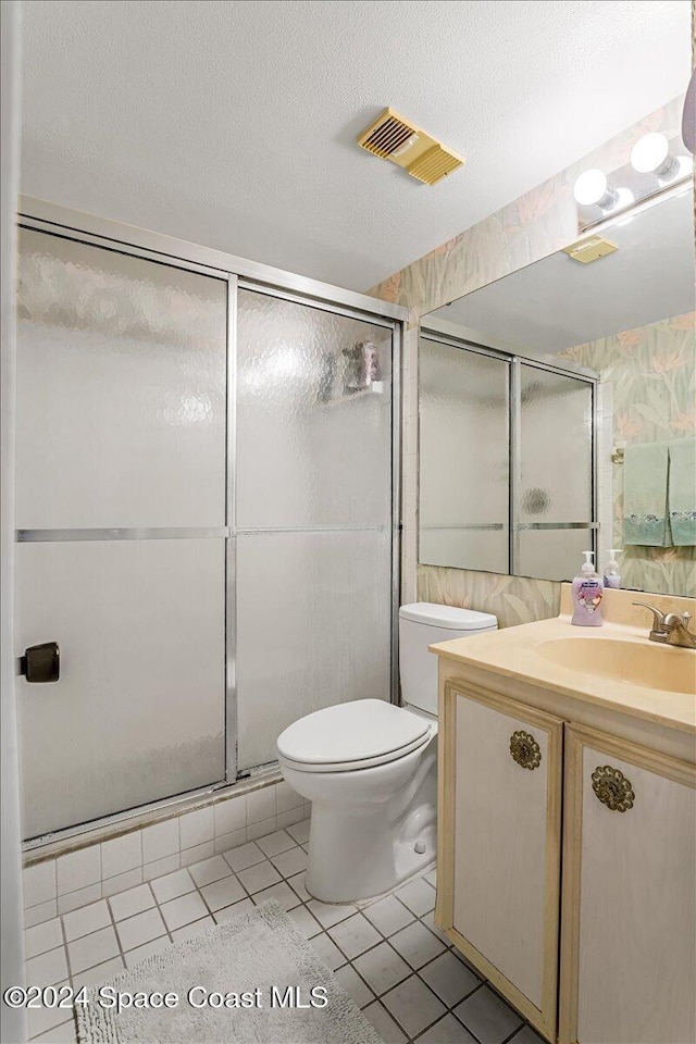 bathroom featuring tile patterned floors, a textured ceiling, vanity, a shower with door, and toilet