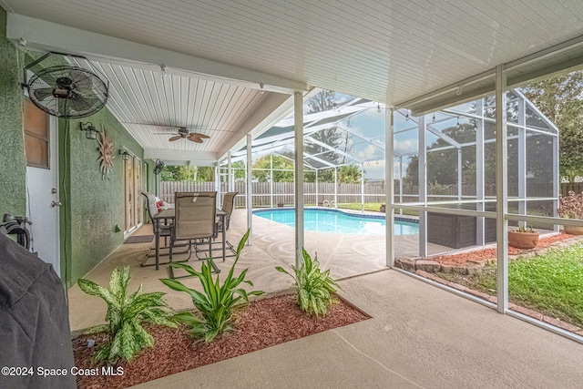 view of pool with glass enclosure, a patio area, and ceiling fan