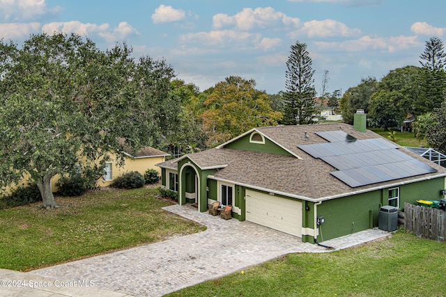 ranch-style house with solar panels, cooling unit, a garage, and a front lawn