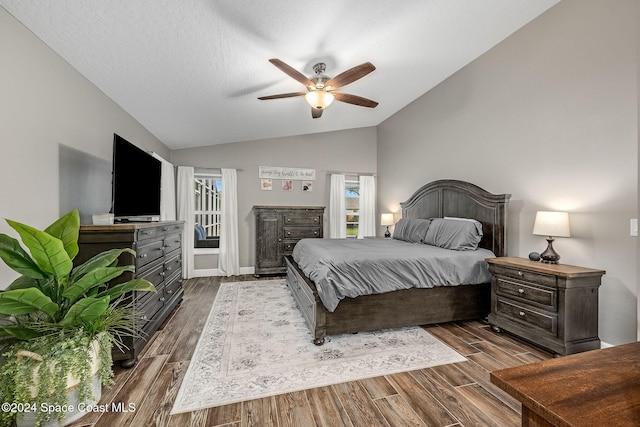 bedroom featuring dark hardwood / wood-style floors, ceiling fan, a textured ceiling, and vaulted ceiling