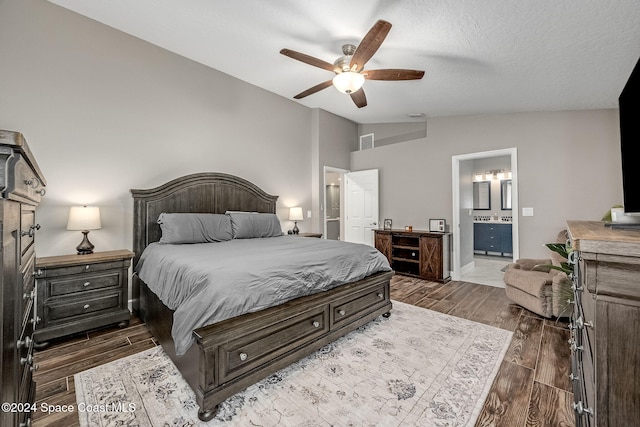 bedroom with lofted ceiling, ceiling fan, a textured ceiling, connected bathroom, and dark hardwood / wood-style flooring