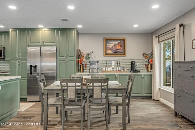 kitchen with green cabinets, light hardwood / wood-style flooring, and appliances with stainless steel finishes