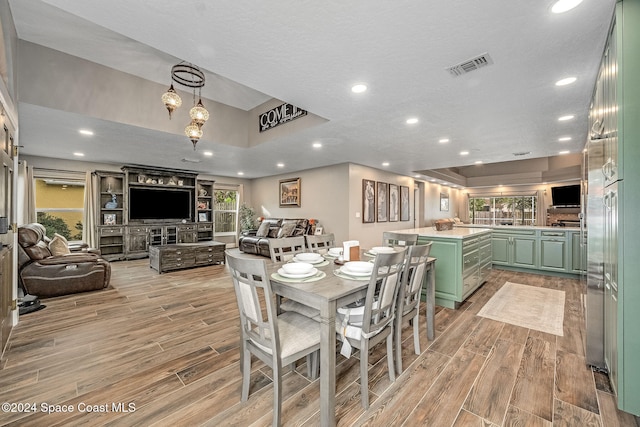 dining area featuring a textured ceiling, light hardwood / wood-style floors, and a healthy amount of sunlight