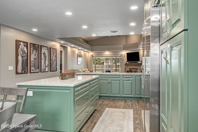 kitchen with dark hardwood / wood-style flooring, backsplash, a textured ceiling, green cabinetry, and a center island