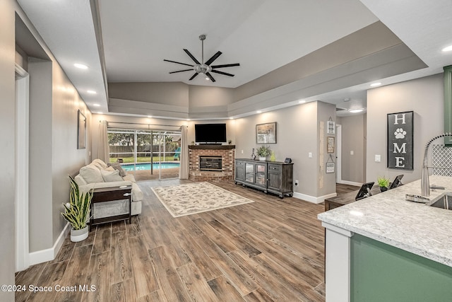 living room featuring lofted ceiling, ceiling fan, wood-type flooring, and a fireplace