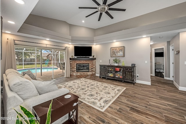 living room featuring ceiling fan, hardwood / wood-style floors, and a brick fireplace