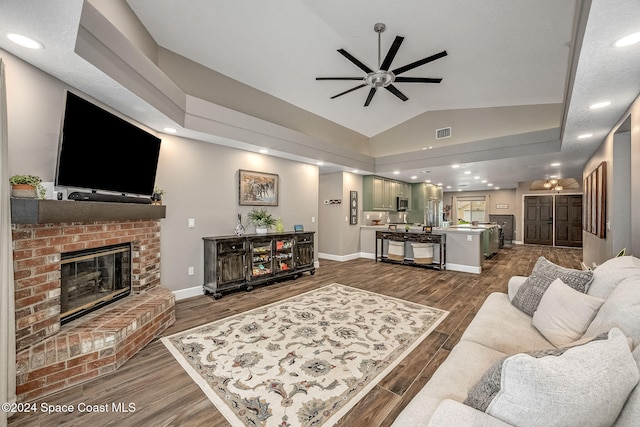 living room featuring ceiling fan, dark hardwood / wood-style flooring, lofted ceiling, and a fireplace