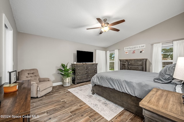 bedroom featuring multiple windows, hardwood / wood-style floors, vaulted ceiling, and ceiling fan