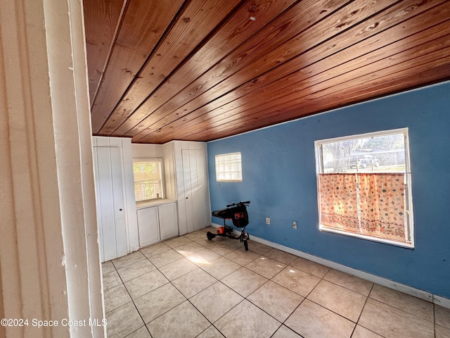 tiled empty room with a healthy amount of sunlight, wood ceiling, and lofted ceiling