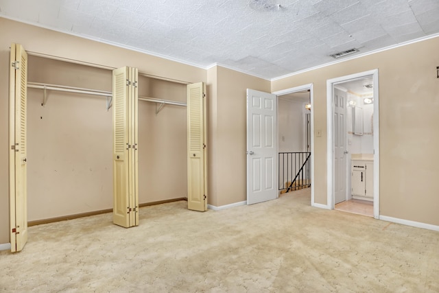 unfurnished bedroom with two closets, carpet floors, ornamental molding, and ensuite bath