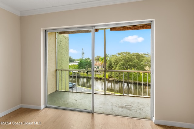 doorway to outside with hardwood / wood-style floors, plenty of natural light, a water view, and ornamental molding