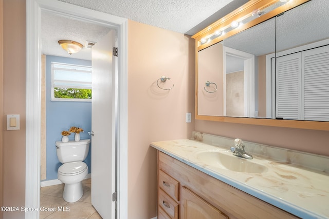 bathroom featuring tile patterned floors, vanity, toilet, and a textured ceiling