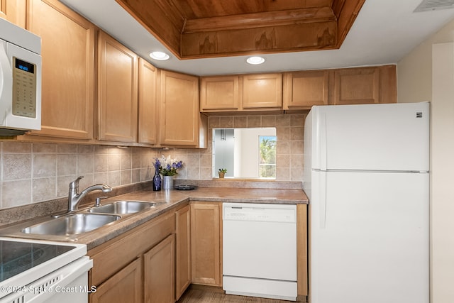 kitchen featuring backsplash, white appliances, a tray ceiling, sink, and light hardwood / wood-style flooring