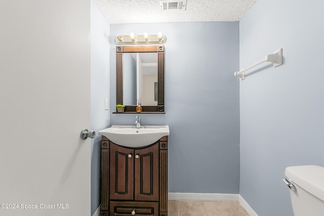 bathroom featuring vanity, a textured ceiling, toilet, and tile patterned flooring