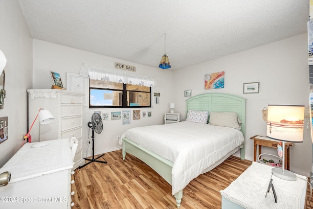 bedroom with a textured ceiling and light wood-type flooring