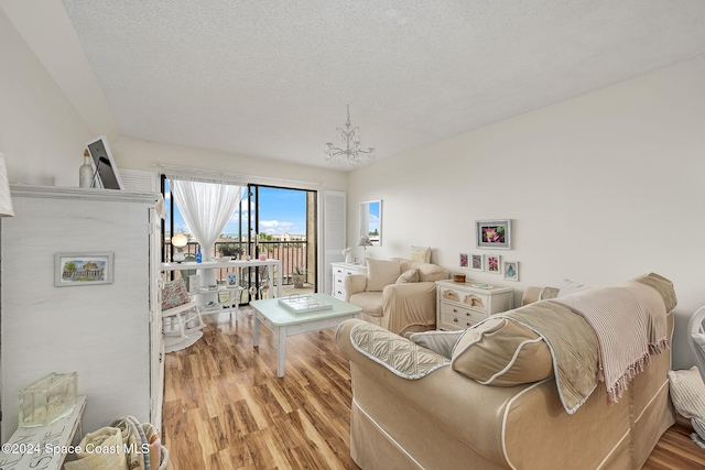 living room featuring a chandelier, a textured ceiling, and light hardwood / wood-style flooring