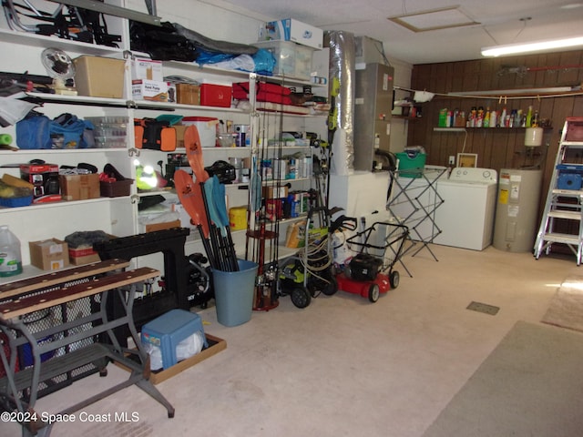 garage with electric water heater, washing machine and dryer, and wood walls