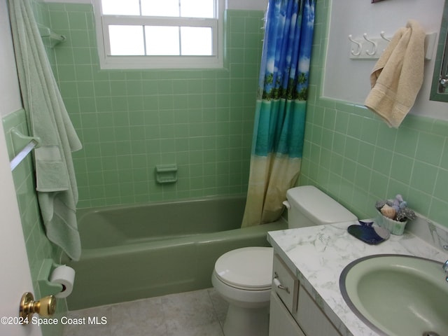 full bathroom with tile patterned floors, vanity, shower / bath combo with shower curtain, tile walls, and toilet