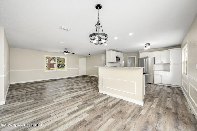 kitchen featuring light wood-type flooring, light stone counters, stainless steel appliances, ceiling fan, and white cabinets