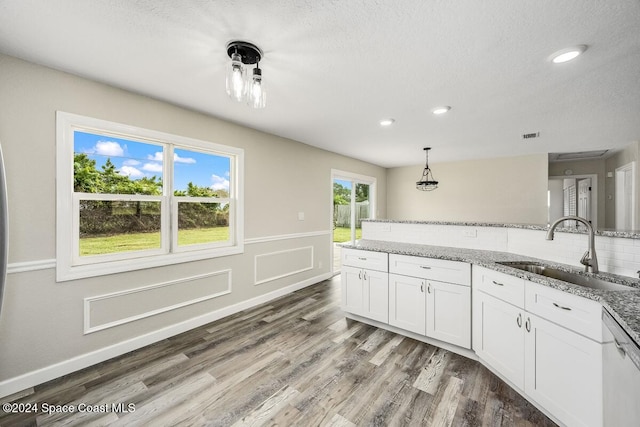 kitchen with dishwasher, sink, decorative light fixtures, white cabinets, and hardwood / wood-style flooring