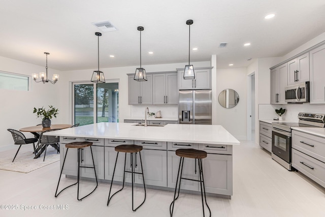 kitchen featuring pendant lighting, sink, a large island with sink, and appliances with stainless steel finishes