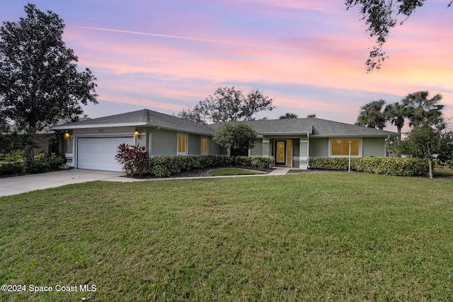 single story home with a garage and a lawn