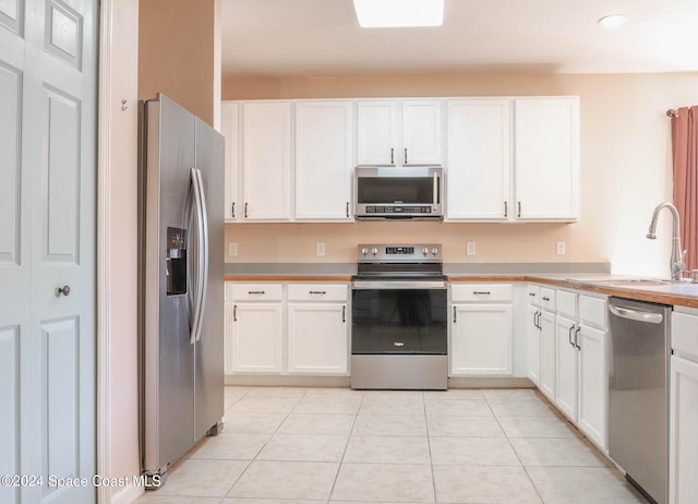 kitchen featuring white cabinetry, sink, light tile patterned floors, and stainless steel appliances