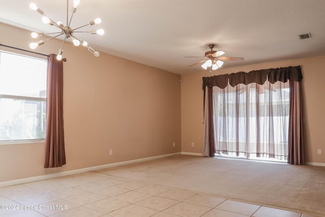 tiled spare room featuring a textured ceiling and ceiling fan with notable chandelier