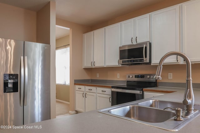 kitchen featuring appliances with stainless steel finishes, white cabinetry, and sink