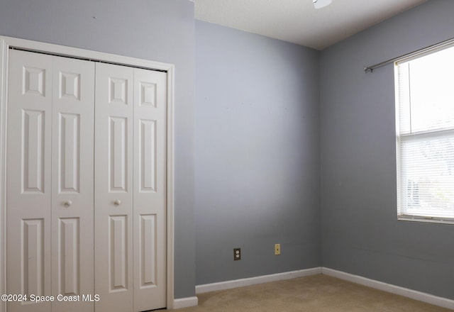 unfurnished bedroom featuring light colored carpet and a closet