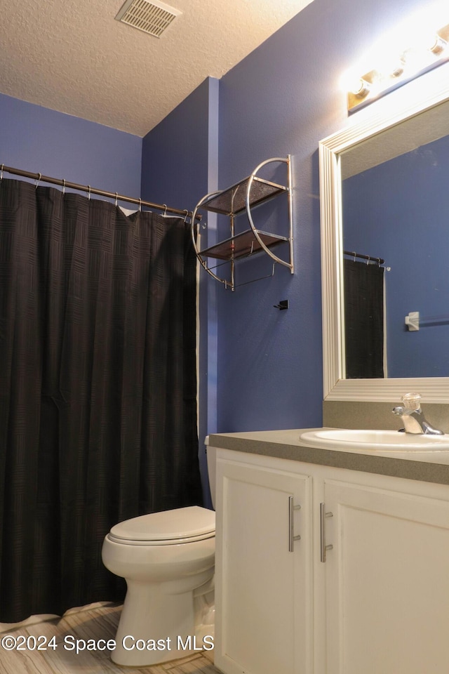 bathroom with vanity, a textured ceiling, and toilet